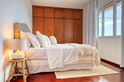 a bedroom with a large bed with a wooden headboard at Clarisse's House I, a Home in Madeira in Ponta do Sol