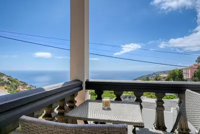 a balcony with a table and chairs and the ocean at Clarisse's House I, a Home in Madeira in Ponta do Sol