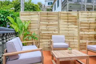 a patio with two chairs and a table and a fence at Clarisse's House I, a Home in Madeira in Ponta do Sol