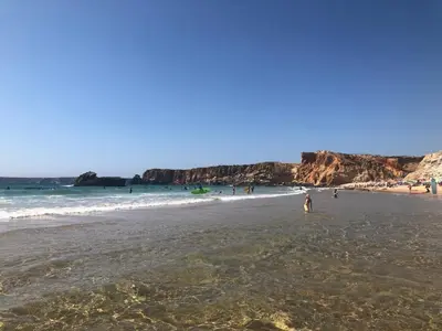 a group of people on a beach near the ocean at Casa da Bisa in Sagres