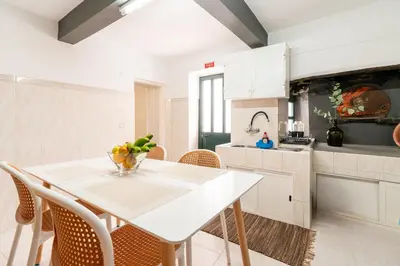 a white kitchen with a white table and chairs at Casa da Tia in Arco da Calheta