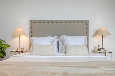 a large bed with white pillows and two lamps at Clarisse's House II, a Home in Madeira in Ponta do Sol