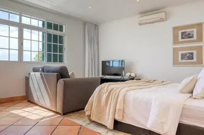 a bedroom with a bed and a couch and a television at Clarisse's House II, a Home in Madeira in Ponta do Sol