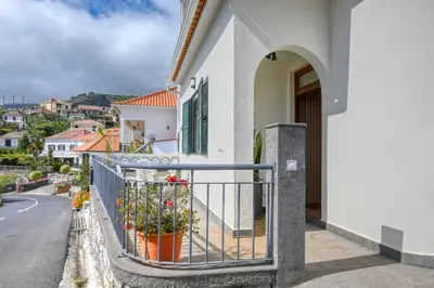 a white house with a fence and flowers on a street at Clarisse's House II, a Home in Madeira in Ponta do Sol