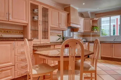 a kitchen with wooden cabinets and a table and chairs at Clarisse's House II, a Home in Madeira in Ponta do Sol