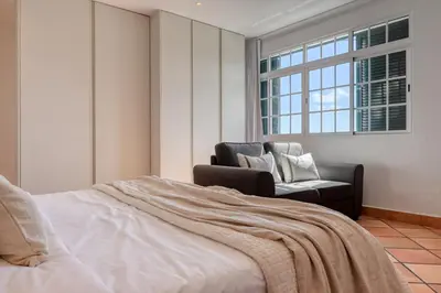 a bedroom with a bed and a chair and a window at Clarisse's House II, a Home in Madeira in Ponta do Sol