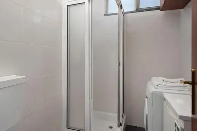 a white bathroom with a shower and a sink at Apartamento América by An Island Apart in Funchal