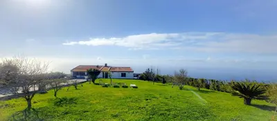 a house on a hill with a green field at Quintinha das Achadas in Achadas da Cruz