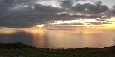 a sunset over a body of water with clouds at Quintinha das Achadas in Achadas da Cruz
