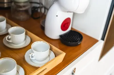 a coffee maker sitting on a counter with cups and saucers at Solar do Ilheuzinho in Câmara de Lobos