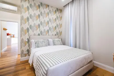 a bedroom with a white bed with a patterned wall at Solar do Ilheuzinho in Câmara de Lobos