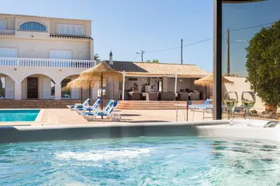 a swimming pool with chairs and a house at Villa Cristallo in Caliços