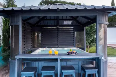 a gazebo with a hot tub in a backyard at Villa Cristallo in Caliços