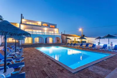 a swimming pool with blue chairs and a building at Villa Cristallo in Caliços