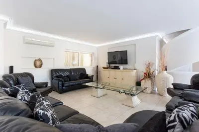 a living room with leather couches and a television at Villa Cristallo in Caliços
