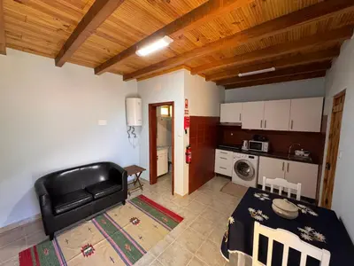 a living room with a black leather couch and a kitchen at Casa do Batista in Seixal