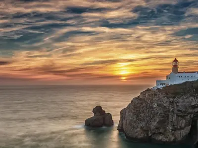 a lighthouse on a cliff near the ocean at sunset at Sagres Mar in Sagres