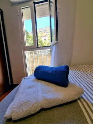 a bed with a blue pillow in a room with a window at Ribeirinho Apartment - Machico Beach in Machico