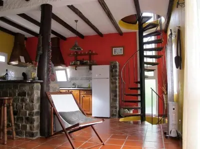 a kitchen with red walls and a spiral staircase at Casa do Bisbis in Lanceiros