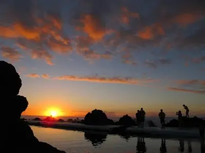 a group of people standing on the beach watching the sunset at Casa do Bisbis in Lanceiros
