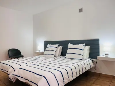 a bedroom with a large bed with striped sheets and pillows at Casa Pão - 5 mins from Machico centre with private parking in Machico