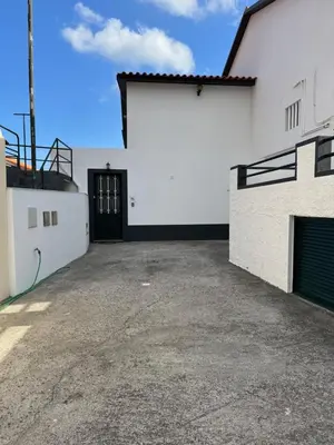 a white building with a black door and a driveway at Casa Pão - 5 mins from Machico centre with private parking in Machico