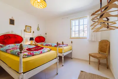 two beds in a room with a table and a chair at Casa Colorida in Vila do Bispo