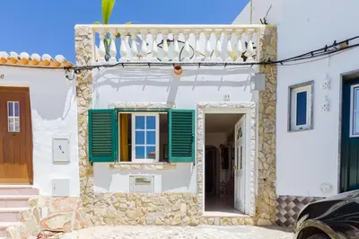 a house with a green window and a balcony at Casa Colorida in Vila do Bispo