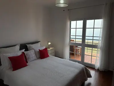 a bedroom with a bed with red pillows and a window at Refúgio dos Prazeres - Madeira Inn Group in Prazeres