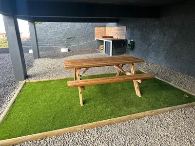 a wooden picnic table sitting on a patch of grass at Refúgio dos Prazeres - Madeira Inn Group in Prazeres