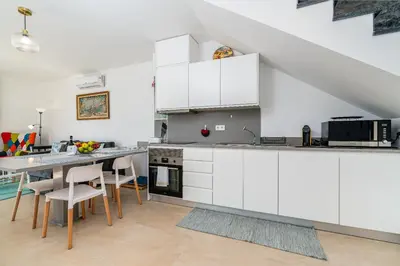 a kitchen with white cabinets and a table with chairs at Mouras House, Arco da Calheta in Arco da Calheta