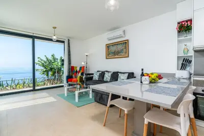 a kitchen and living room with a table and chairs at Mouras House, Arco da Calheta in Arco da Calheta