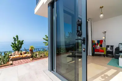a glass door of a house with a view of the ocean at Mouras House, Arco da Calheta in Arco da Calheta