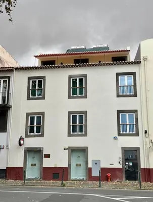 a white building with four doors and a fire hydrant at Old Zone Apartment - 1º C in Funchal