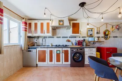a kitchen with a washing machine and a table at Casa tempo e amor in Vila do Bispo