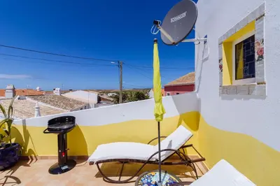 a patio with a chair and an umbrella on a balcony at Casa tempo e amor in Vila do Bispo