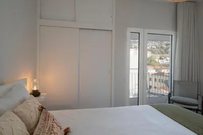 a bedroom with a white bed and a balcony at Apartamento Jaime Moniz by An Island Apart in Funchal