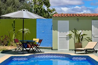 a pool with a table and chairs and an umbrella at Private renovated APT w pool, 3m to praia da Luz in Valverde