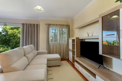 a living room with a couch and a flat screen tv at Refugio Dourado in Água de Pena