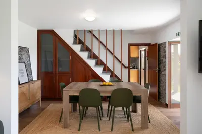 a dining room with a wooden table and green chairs at Casa de Pedra by An Island Apart in Ribeira Brava