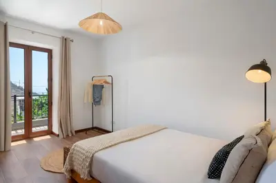 a white bedroom with a bed and a balcony at Casa de Pedra by An Island Apart in Ribeira Brava