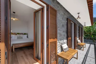 a room with a balcony with a bed and chairs at Casa de Pedra by An Island Apart in Ribeira Brava