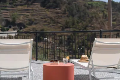 two chairs and a table with a drink and a hat at Casa de Pedra by An Island Apart in Ribeira Brava
