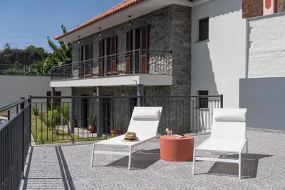 two white chairs on a patio in front of a house at Casa de Pedra by An Island Apart in Ribeira Brava