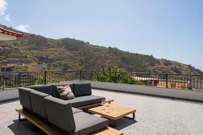 a couch and a coffee table on a balcony with a mountain at Casa de Pedra by An Island Apart in Ribeira Brava
