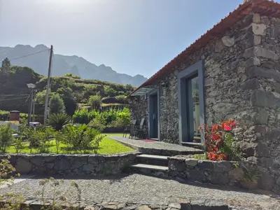 a gray garage door with a window in a stone wall at Casa da Marica in São Vicente