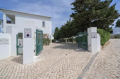 a white building with a gate and a tree at 3 bedroom Beach House in Luz in Luz