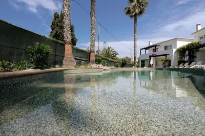 a swimming pool with palm trees and a building at 3 bedroom Beach House in Luz in Luz