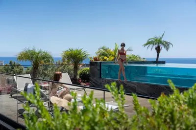 a woman in a bikini standing on the edge of a swimming pool at Savoy Insular Loft by An Island Apart in Funchal