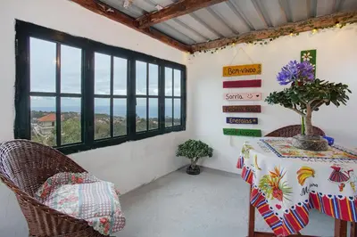 a dining room with a table and chairs and windows at Luci's House in São Jorge